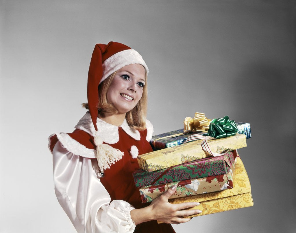 Detail of 1960s Young Woman In Red And White Santa Helper Costume And Hat Holding Pile Of Wrapped Christmas Presents Studio by Anonymous