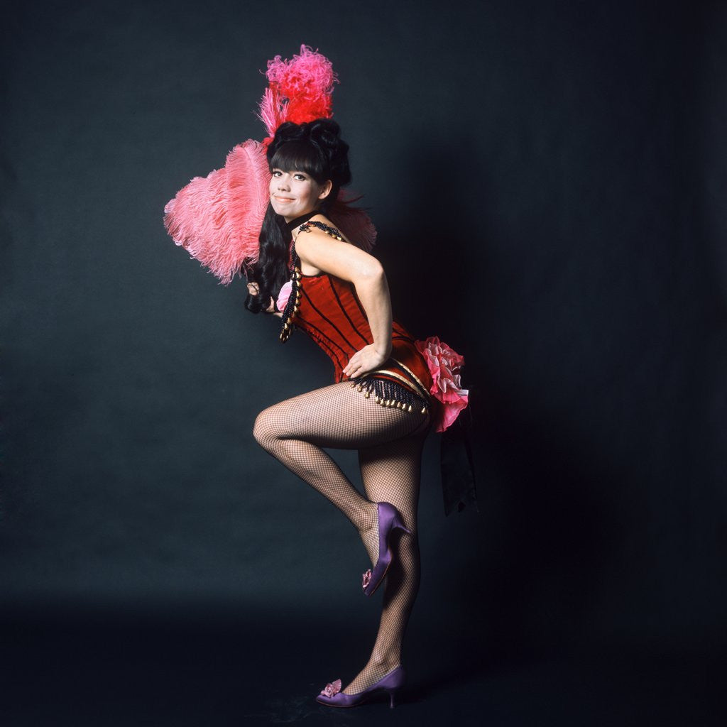 Detail of 1960s Woman In American 1890s 1900s Wild West Saloon Showgirl Style Costume With Pink Ostrich Feather Fan Looking At Camera by Corbis