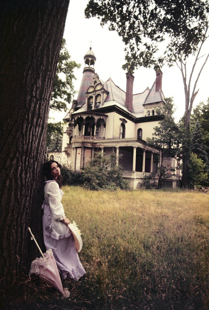 Detail of 1960s 1970s Woman Standing Beside Tree Front Of Abandoned Haunted Victorian House by Anonymous