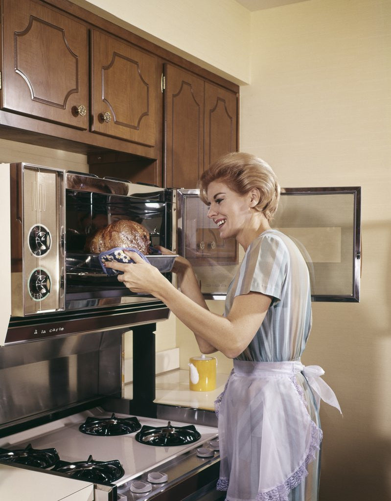Detail of 1960s Woman Housewife In Apron Oven Baking Cooking Roast In Kitchen by Corbis