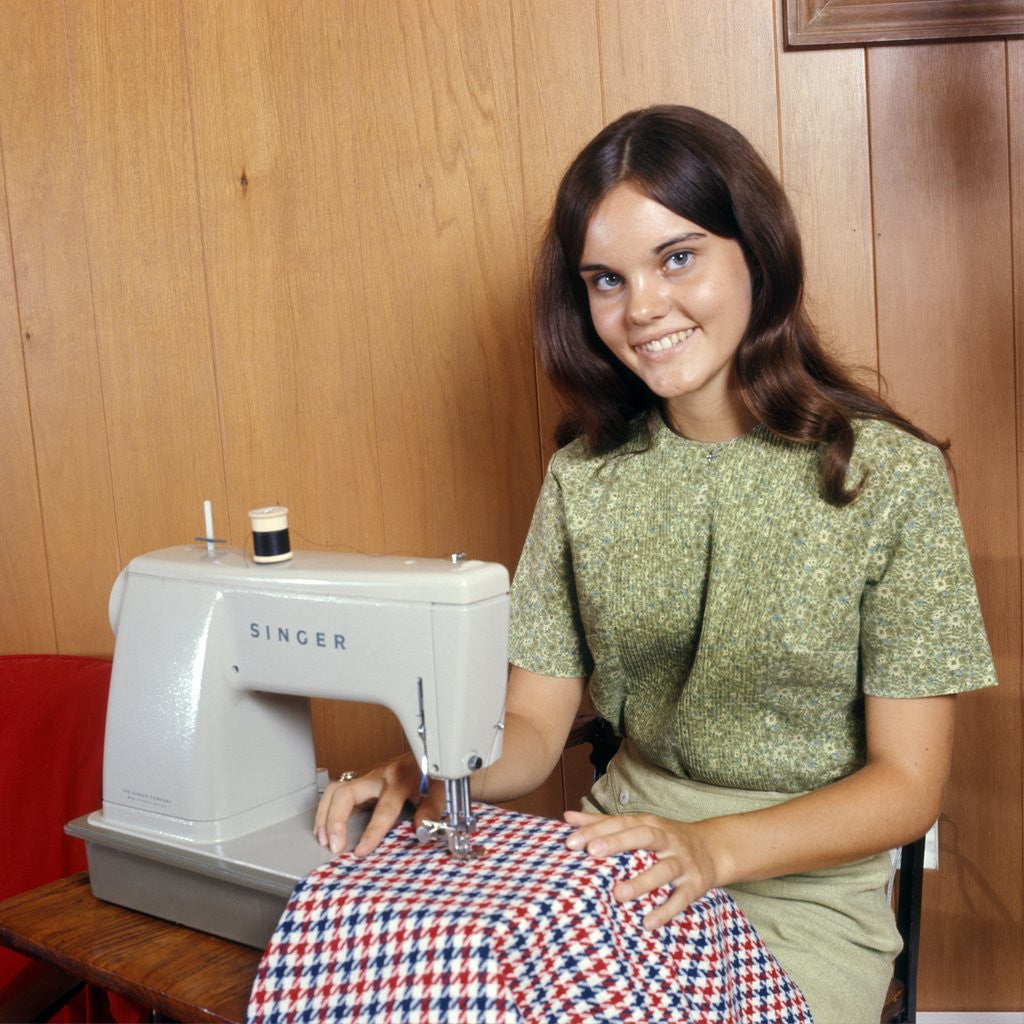 Detail of 1970s Young Woman Teenager Using A Singer Sewing Machine Looking At Camera by Anonymous