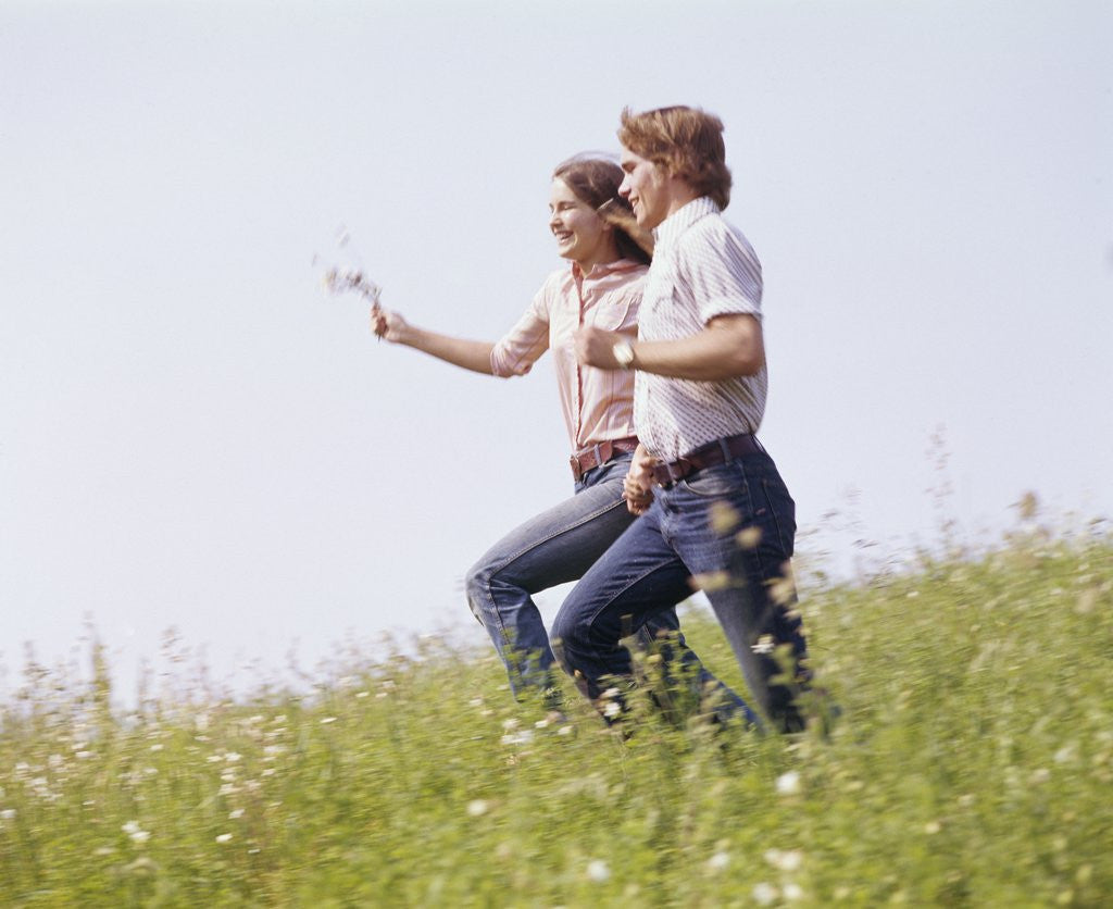 Detail of 1970s Couple Running Holding Hands Field by Corbis
