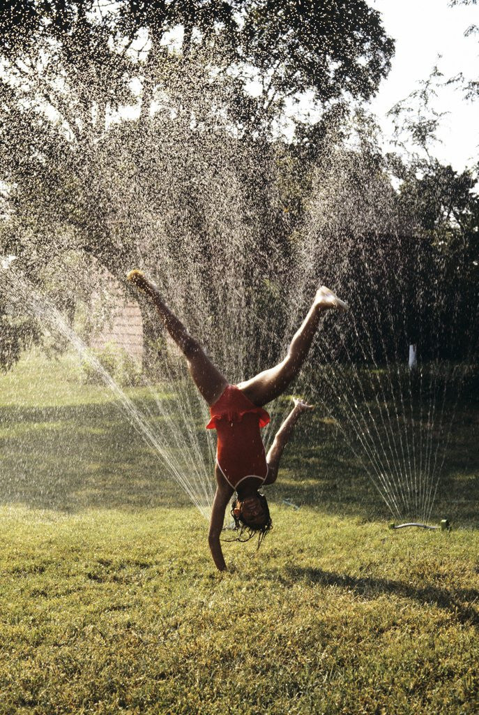 Detail of 1980s Little Girl Cart Wheeling Through Lawn Sprinklers by Anonymous