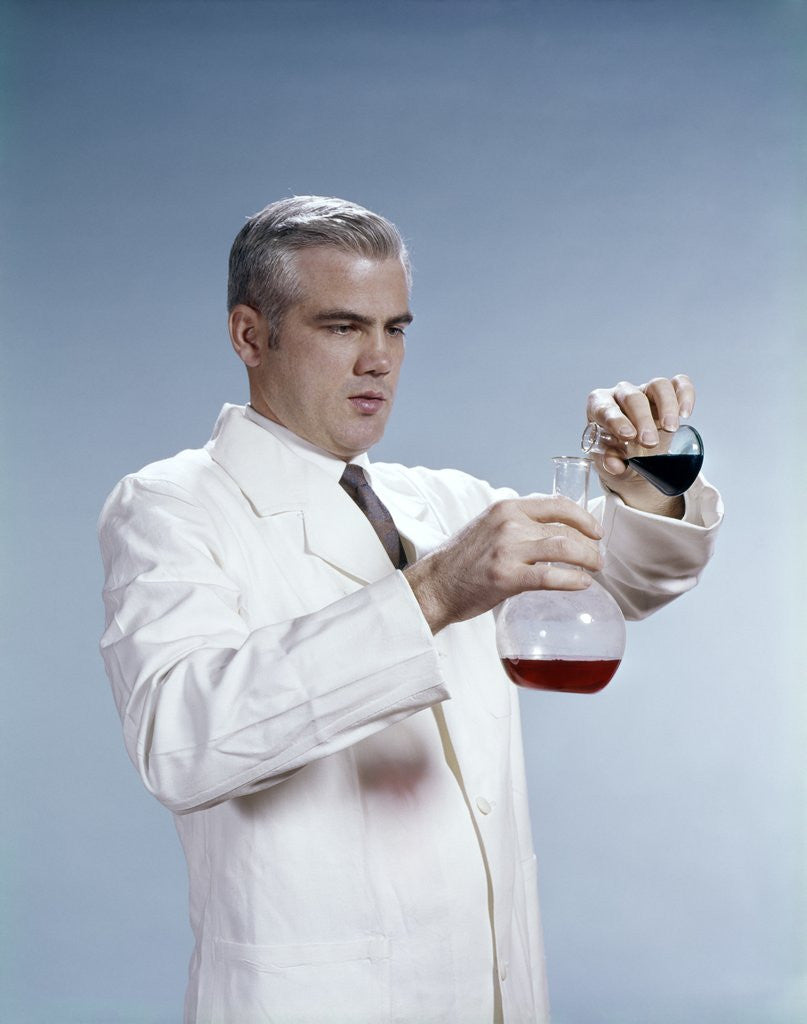 Detail of 1960s Man Wearing Lab Coat Pouring Liquid From Small Erlenmeyer Flask Into A Larger Flask by Corbis