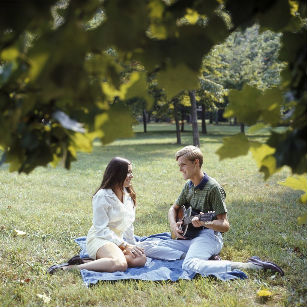 Detail of 1960 1960s 1970 1970s Retro Smiling Couple Man Woman Sitting On Blanket On Grass Park Man Playing Acoustic Guitar by Anonymous