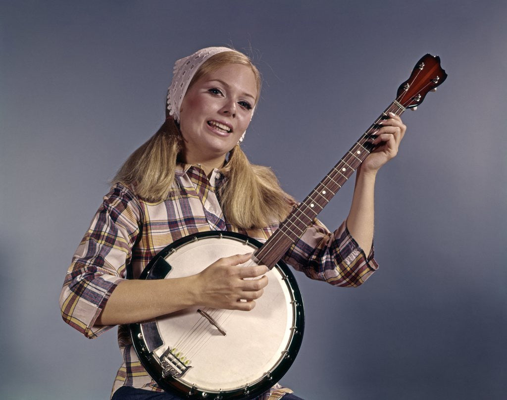 Detail of 1960s Young Blonde Woman Wearing Plaid Shirt Playing Banjo Singing Folk Music Looking At Camera by Anonymous