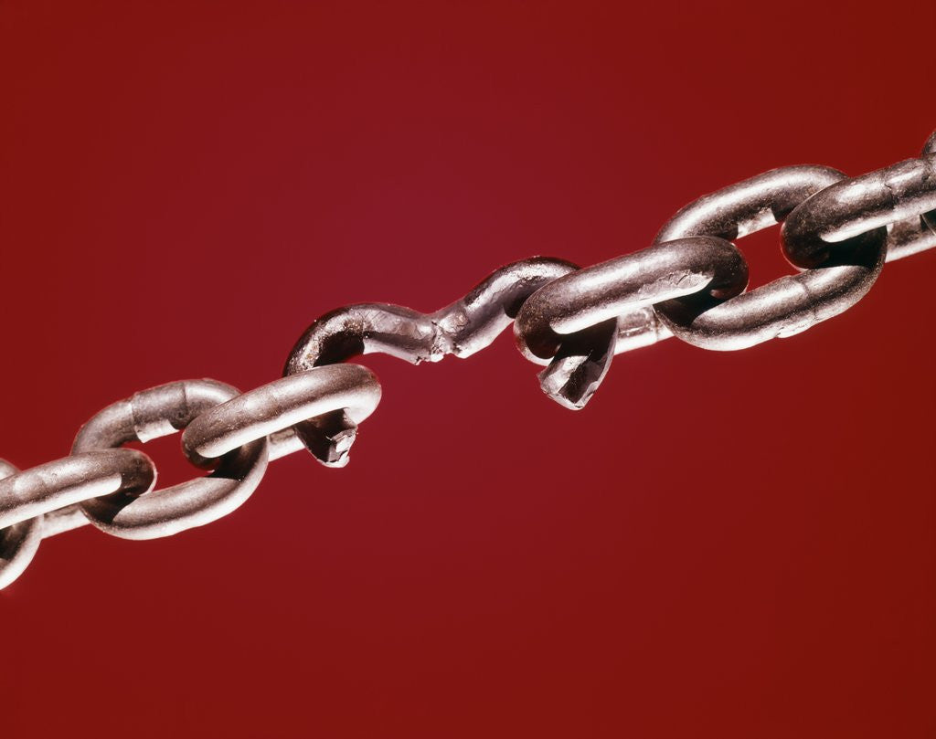 Detail of broken Chain With Weak Link On Red Background by Corbis