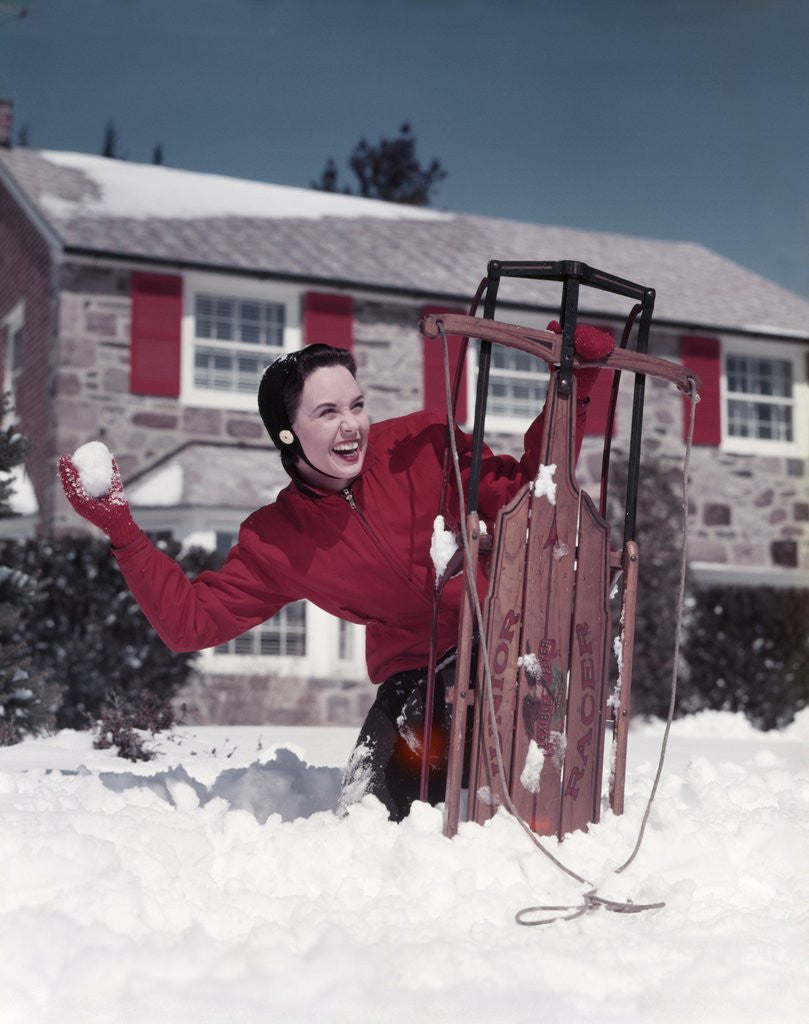Detail of 1950s Woman Hiding Behind Sled Throwing Snowball Front Stone House by Anonymous