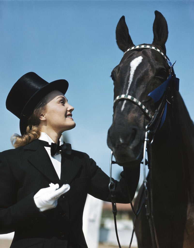 Detail of 1940s 1950s Smiling Woman Wearing Top Hat Tuxedo White Gloves Holding Riding Crop Posing With Horse Blue Ribbon Winner by Corbis