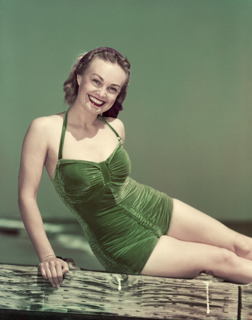 Detail of 1940s Portrait Smiling Woman Wearing Green Velvet Bathing Suit Sitting Posing On Diving Board by Anonymous