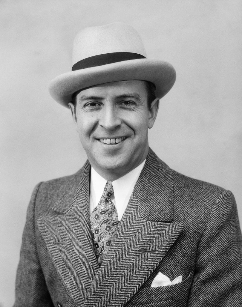 Detail of 1930s Head & Shoulder Portrait Of Smiling Man In Herringbone Suit Paisley Tie & White Hat by Corbis