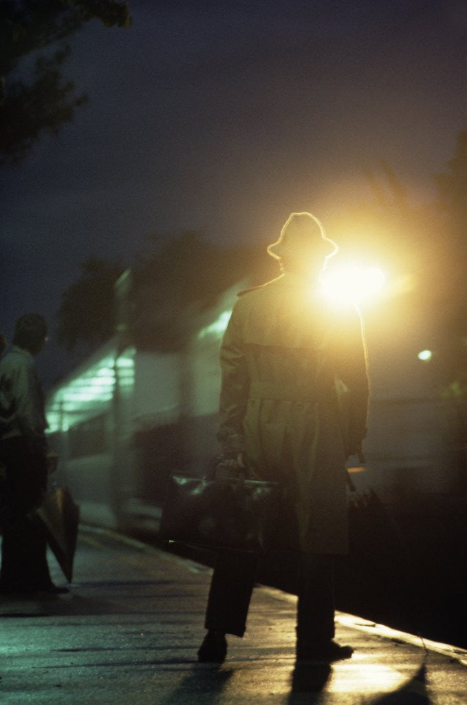 Detail of 1970s 1980s Anonymous Man Commuter Waiting For Train Silhouetted By Bright Light by Anonymous