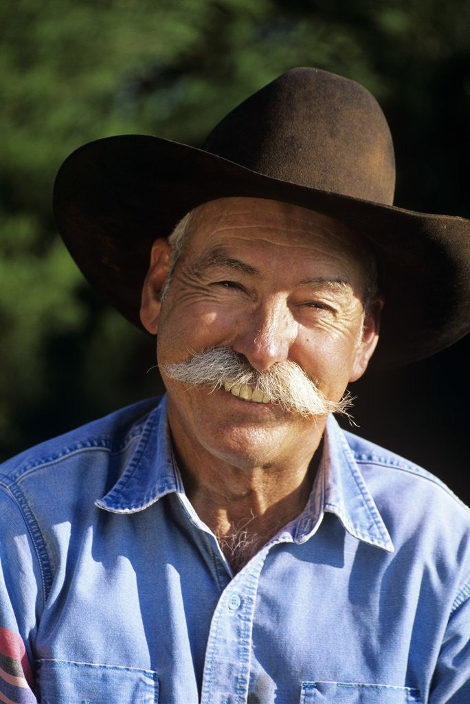 Detail of 1990s Portrait Of Smiling Cowboy With Gray Mustache Black Hat Blue Shirt Looking At Camera by Corbis