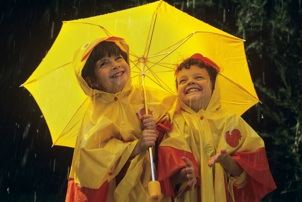 Detail of 1990s Two Laughing Young Girls Holding A Yellow Umbrella And Wearing Yellow Rain Ponchos by Corbis