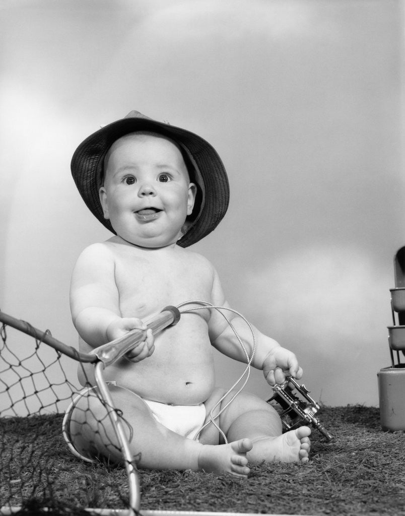 Detail of 1960s Baby Girl Wearing Fishing Hat Holding Net And Reel Fishing Gear Looking At Camera by Corbis
