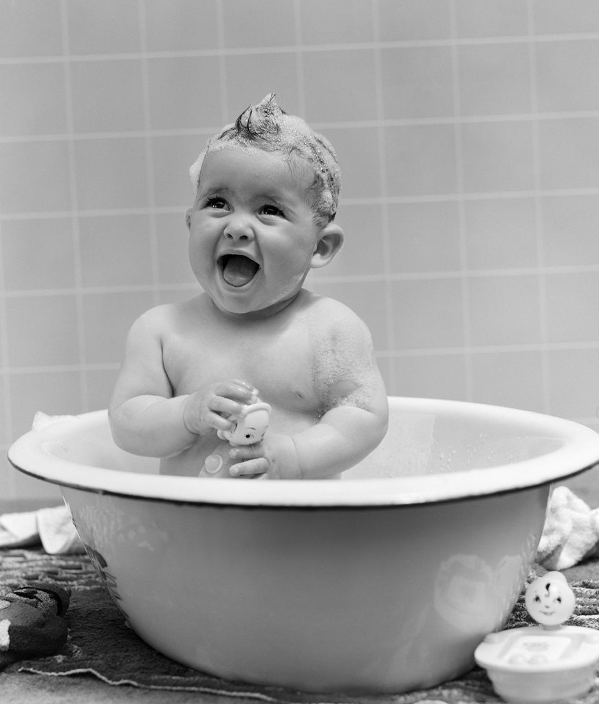 Detail of 1940s Smiling Baby In Bath Covered In Soap Suds Laughing Holding Toy by Corbis