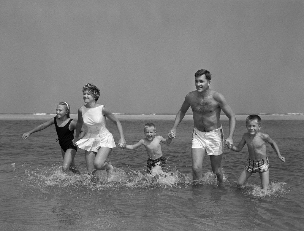 Detail of 1960s Family Holding Hands Running Together In Water At Seashore by Anonymous