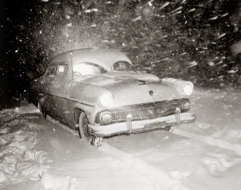 Detail of 1950s Snow Covered Automobile Driving On Road In Deepening Winter Blizzard Snow by Anonymous