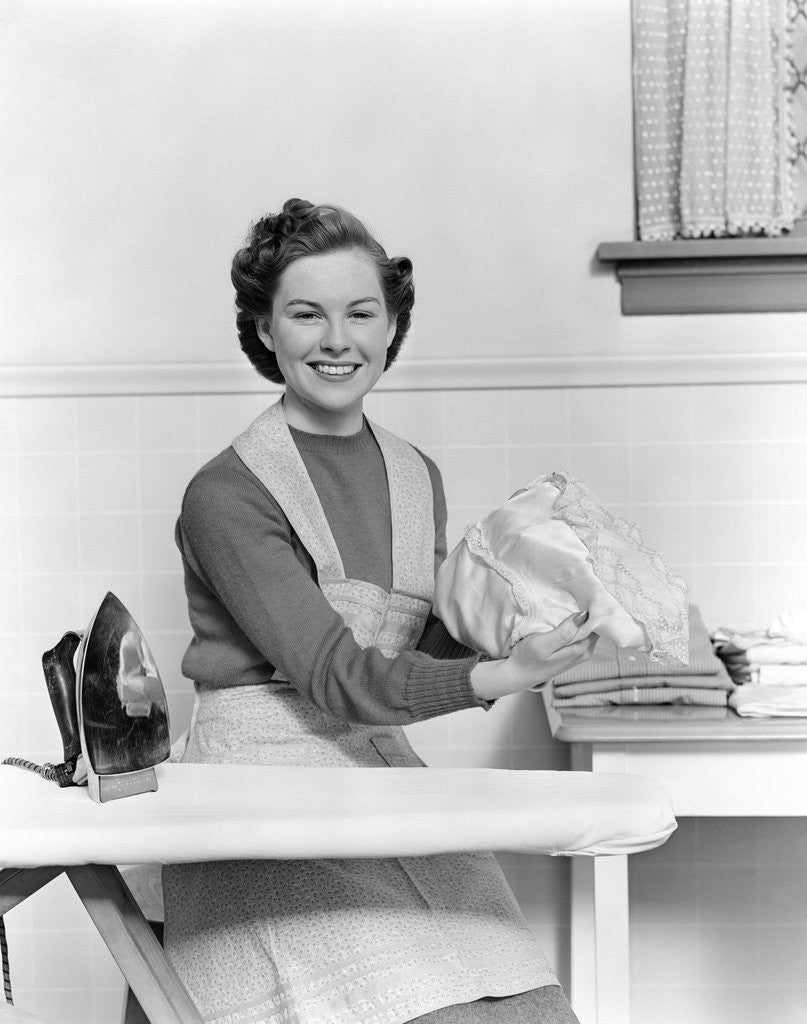 Detail of 1940s Woman Sitting At Ironing Board Smiling Looking At Camera by Corbis