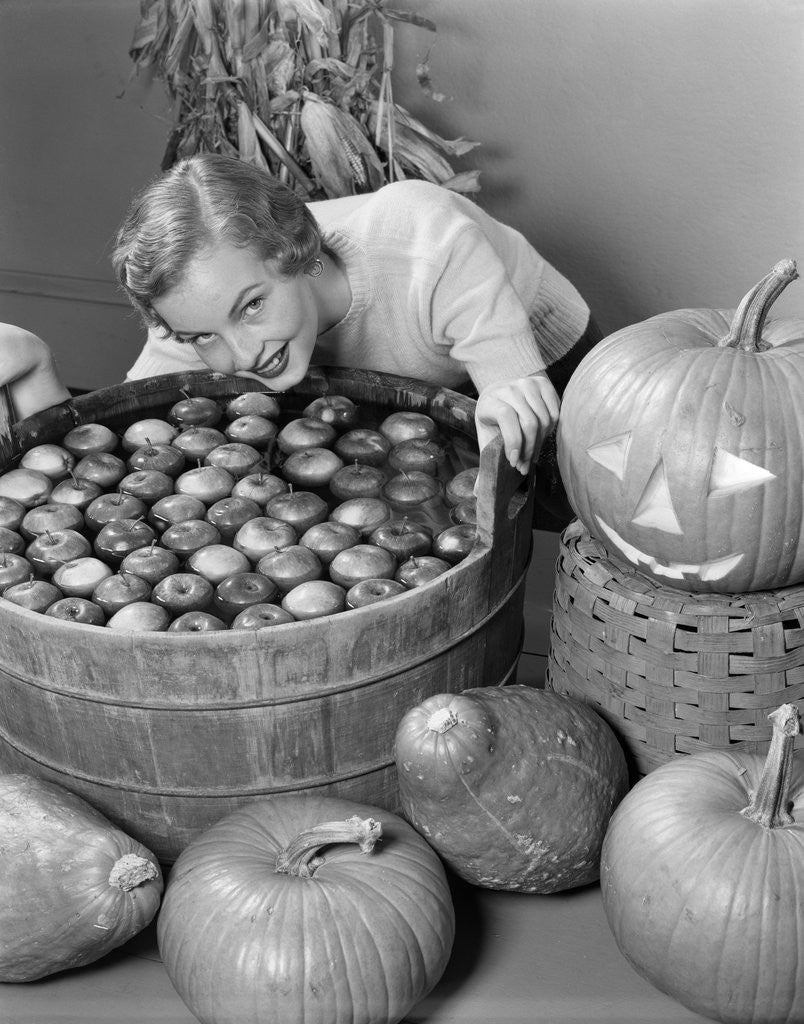 Detail of 1950s Smiling Woman Leaning Over Wooden Tub Filled With Water About To Begin Bobbing For Apples by Anonymous