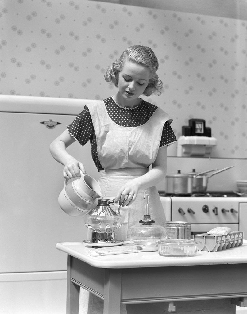 Detail of 1930s Woman In Kitchen Wearing Apron Making Breakfast Pouring Water Into Coffee Pot by Corbis