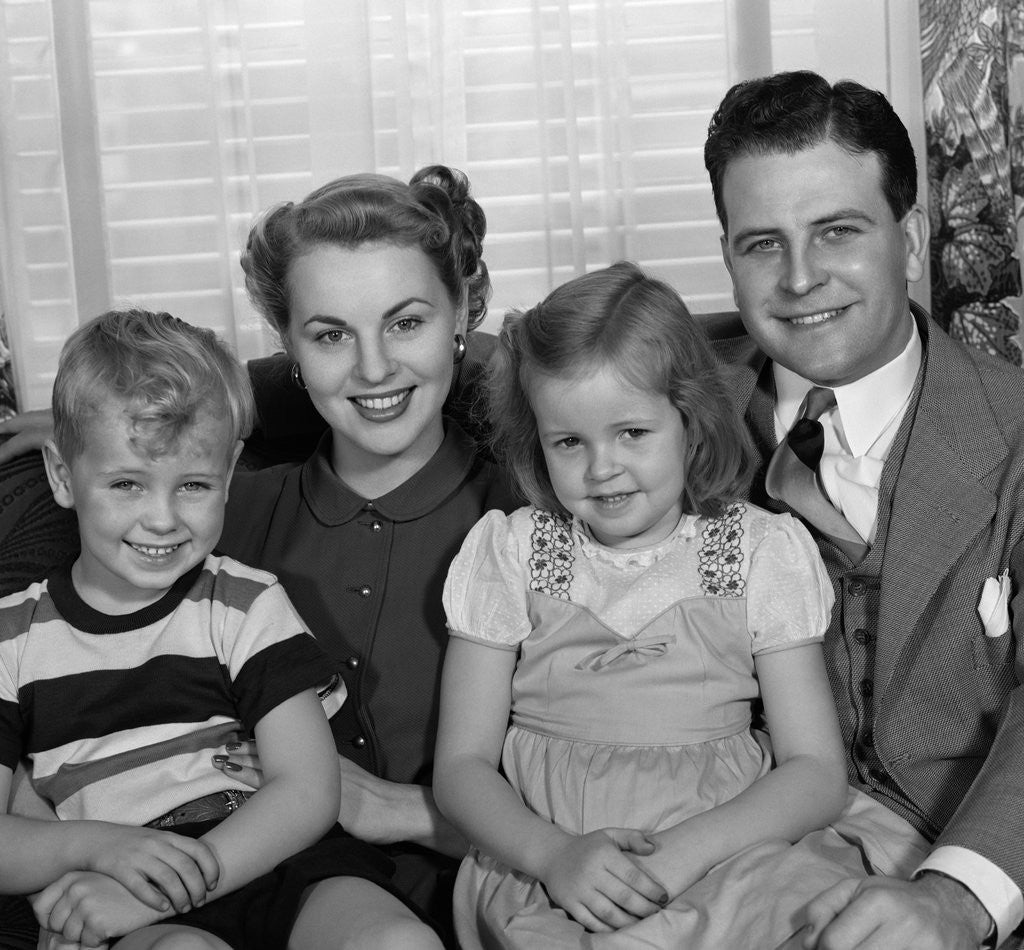 Detail of 1940s 1950s Portrait Of Smiling Family Man Woman Boy Girl Sitting On Sofa Looking At Camera by Anonymous