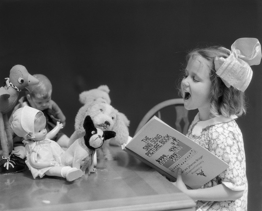 Detail of 1930s Enthusiastic Little Girl Big Bow Ribbon In Her Hair Singing To Assembled Group Of Dolls Toys And Stuffed Animals by Anonymous