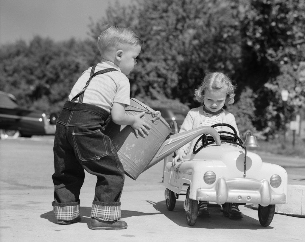 Detail of 1950s Little Boy Playing Gas Station Pouring Water Into Toy Car For Little Girl by Anonymous