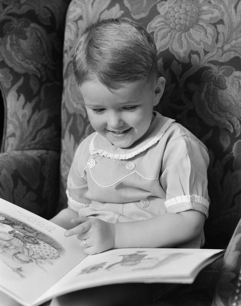 Detail of 1930s 1940s Little Boy Sitting On Chair Reading Picture Book by Corbis