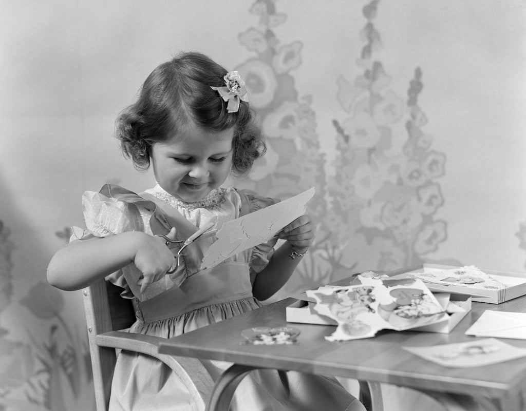 Detail of 1940s Smiling Little Girl Cutting Paper With Scissors by Anonymous