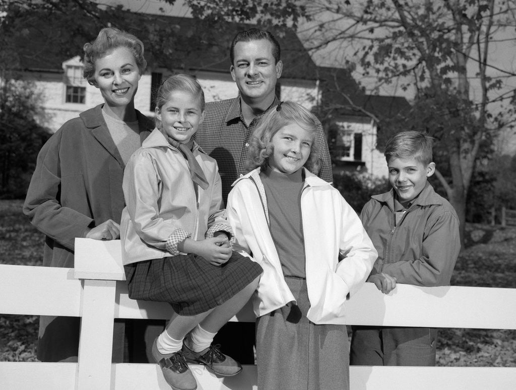 Detail of 1960s Portrait Smiling Family Father Mother Two Daughters Son By White Fence In Front Of Suburban House In Autumn by Anonymous