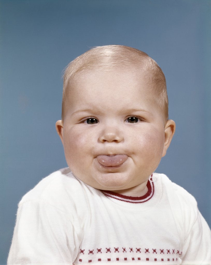 Detail of 1960s Portrait Of Cute Blond Chubby Baby Looking At Camera Sticking Out Tongue by Anonymous