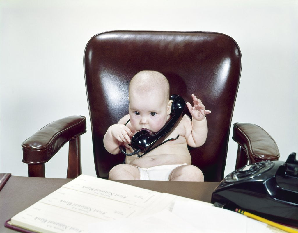 1960s Chubby Baby Sitting In Leather Office Chair Behind Desk Holding Talking On Telephone