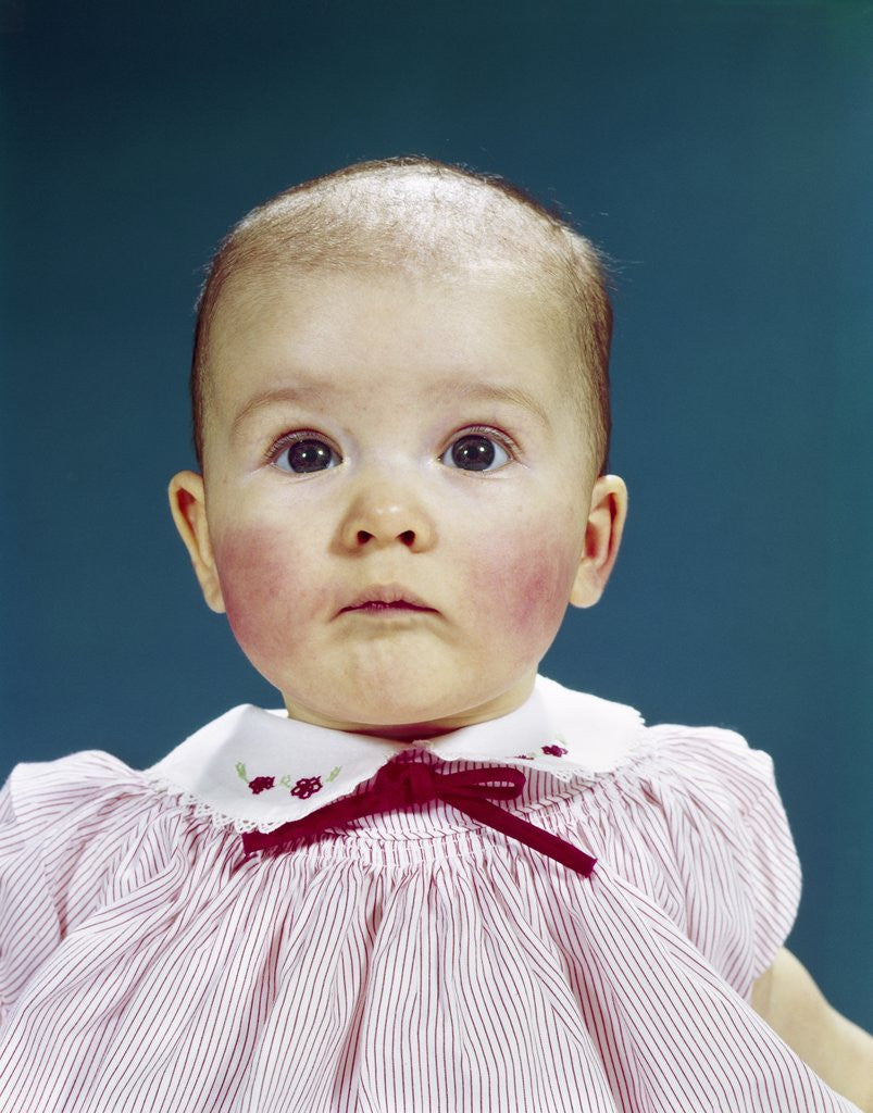 Detail of 1960s Portrait Baby Girl Silly Facial Expression Red Bow At Collar Looking At Camera by Anonymous