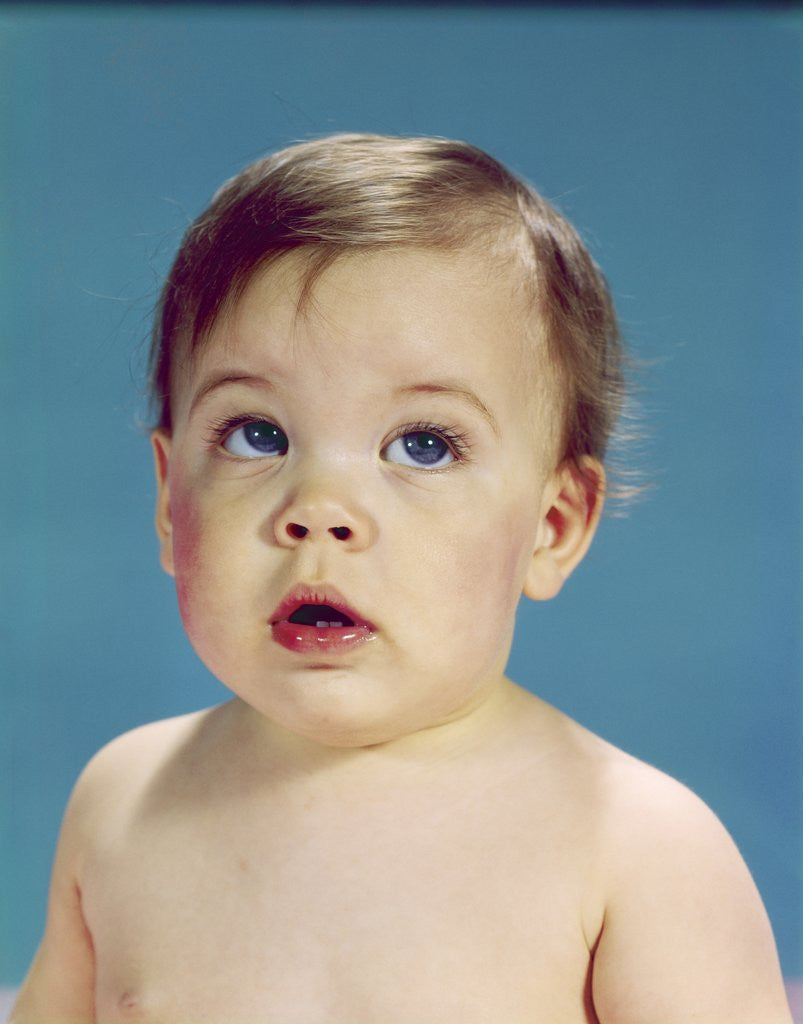 Detail of 1960s Baby With Uncertain Facial Expression Deep Blue Eyes Looking Guilty Up And To The Side by Anonymous