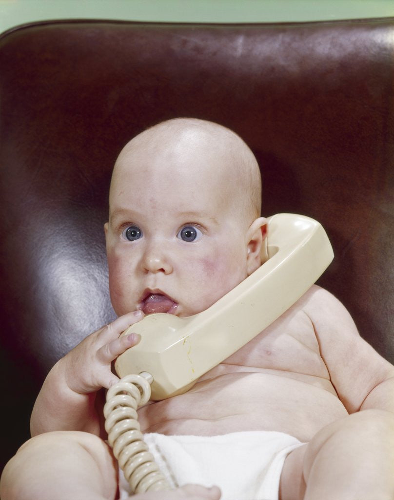 Detail of 1960s Chubby Baby Sitting In Leather Office Chair Talking On Telephone by Corbis