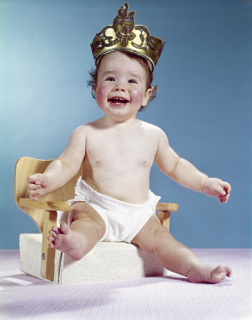 1960s Smiling Happy Baby Wearing Crown Sitting On Booster Seat