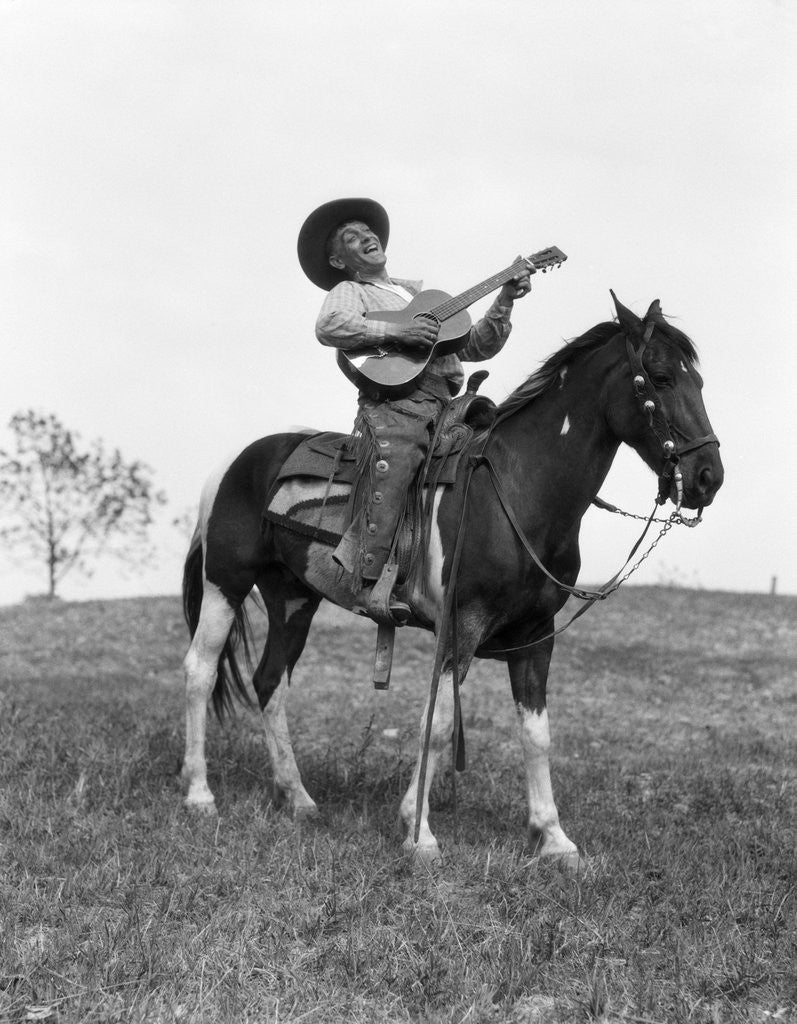 Detail of 1920s cowboy on horse singing and playing guitar by Corbis