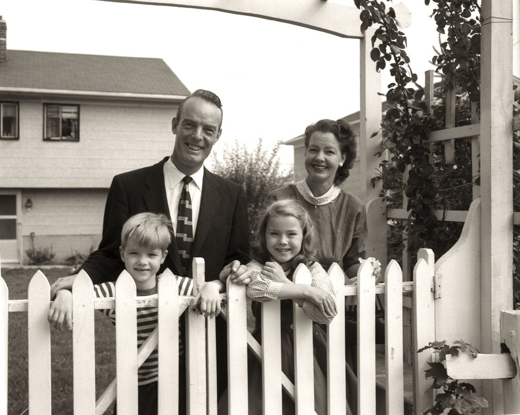 Detail of 1950s family of four behind picket fence by Anonymous