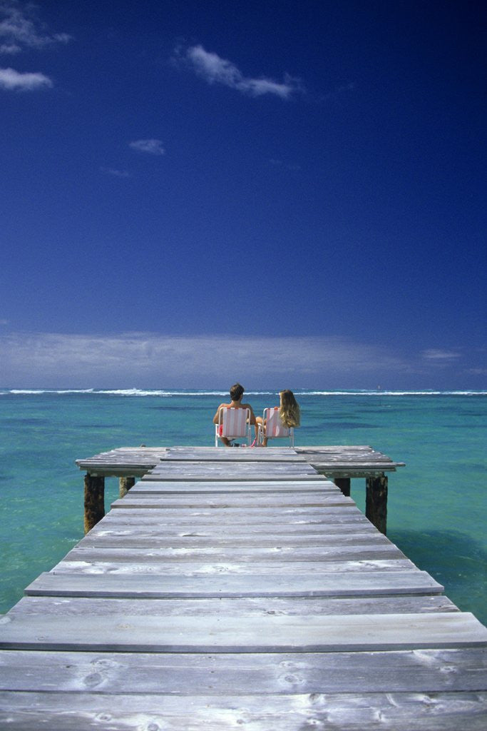 Detail of couple Sitting On A Pier In An Ocean Lagoon by Corbis