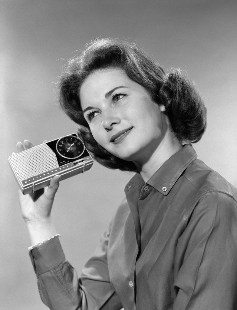 Detail of 1960s smiling teenage girl listening to portable radio by Anonymous