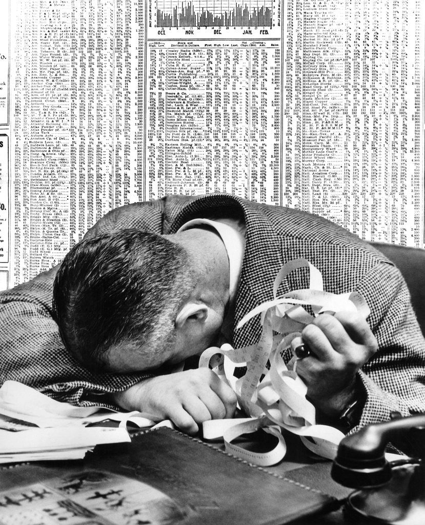 Detail of 1930s man with head on his desk holding stock ticker tape by Anonymous