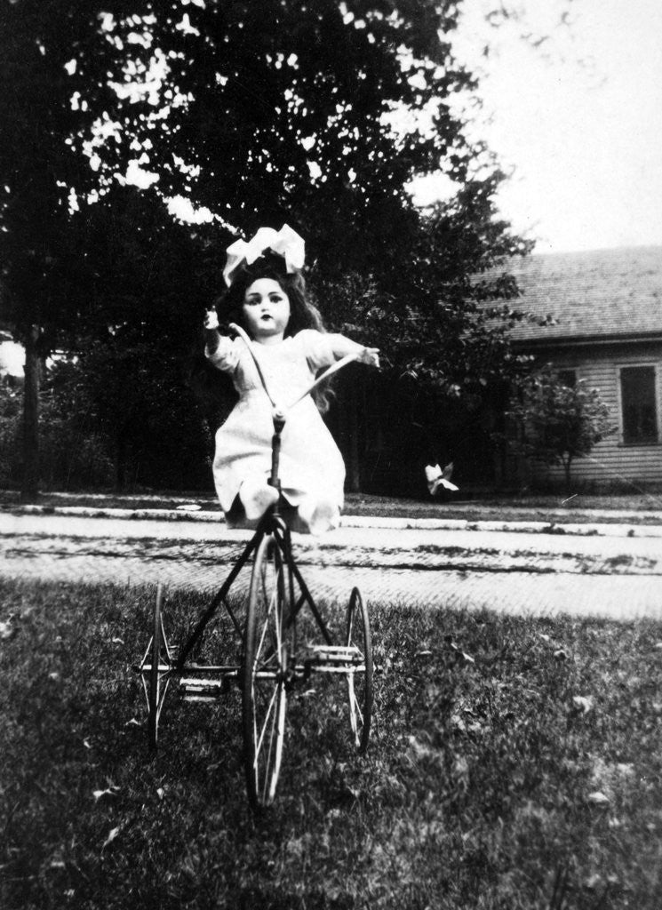 Detail of Large play doll sits on a period tricycle, ca. 1925. by Corbis