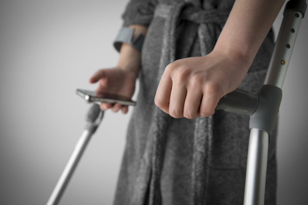 Detail of Person on crutches texting by Anonymous