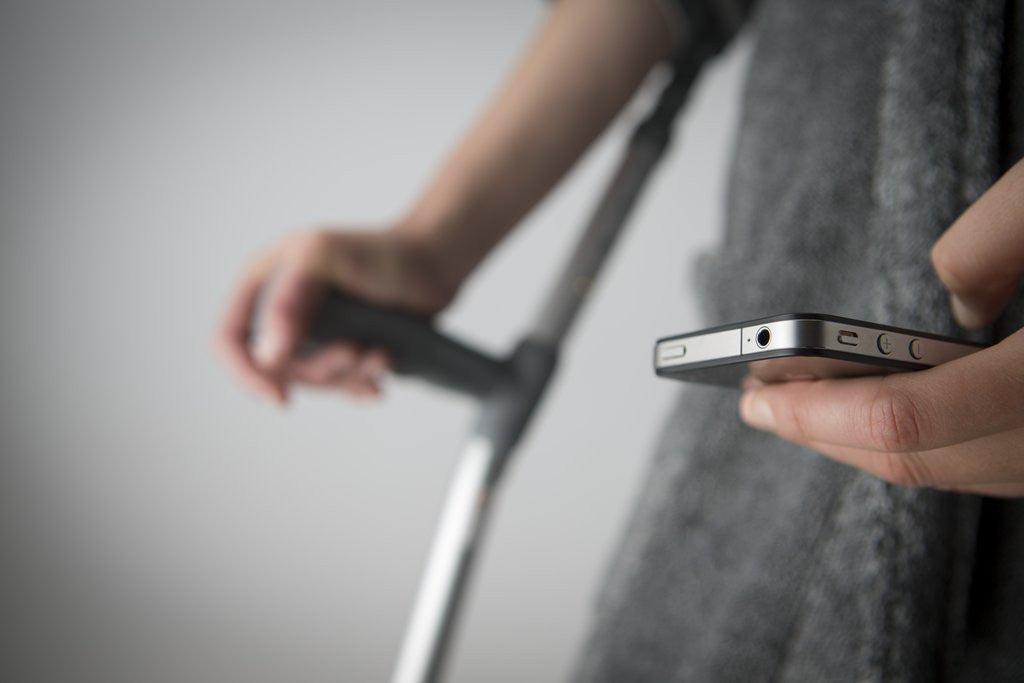 Detail of Person on crutches texting by Anonymous