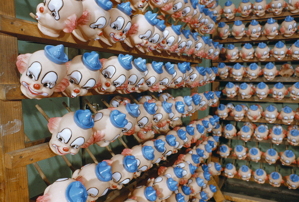 Detail of Clown Heads on Rack in Factory by Corbis