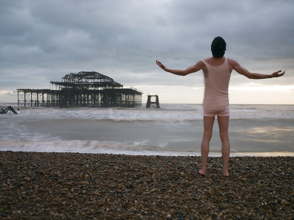 Detail of Man standing on beach with outstretched hands, rear view, Brighton by Assaf Frank
