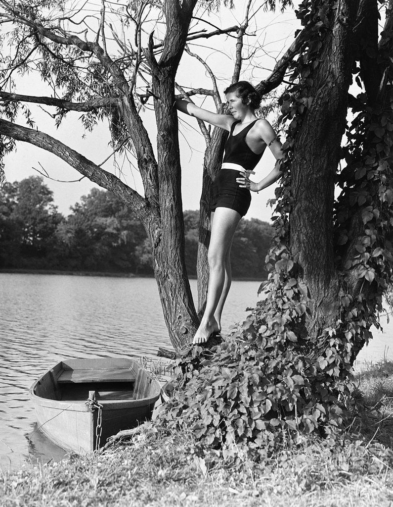 Woman Standing in Tree by Lake by Corbis