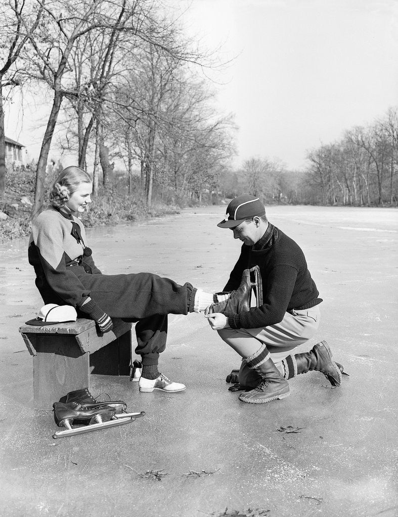 Detail of Man Putting on Woman's Ice Skates by Corbis