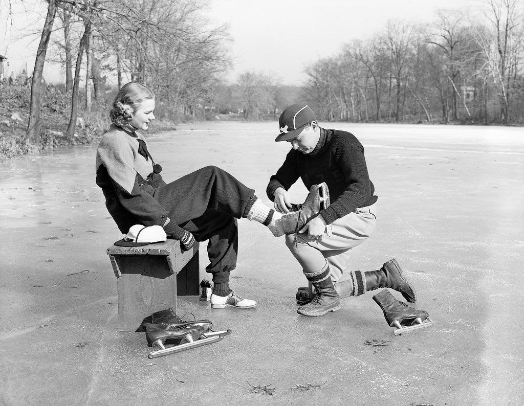 Man Putting on Woman's Ice Skates by Corbis